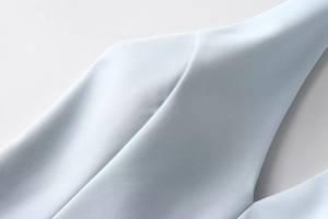 Detailed close-up of light blue sleeveless dress neckline with fine stitching and fabric texture