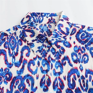 Détail du col de la chemise avec motifs ethniques bleus et boutons blancs sur le devant