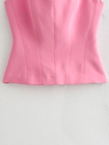 Detail of pink corset top with vertical slimming seams and soft woven fabric texture