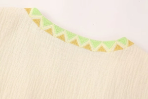 Close-up of bohemian neckline with yellow and green geometric triangle embroidery