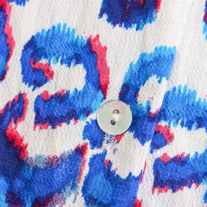 Macro du tissu à imprimé léopard coloré avec un bouton en nacre sur le détail du haut