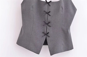 Détail du haut gris sans manches avec nœuds noirs et ourlet en forme de V inversé