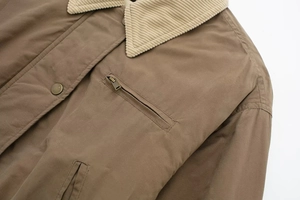 Detail of beige corduroy collar and metal zipper pocket on brown bomber jacket