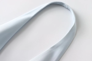 Macro detail of high-quality stitching on light blue sleeveless dress shoulder strap