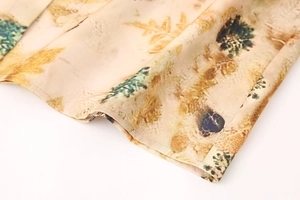 Close-up of silky fabric with natural landscape print and neat stitching on hemline