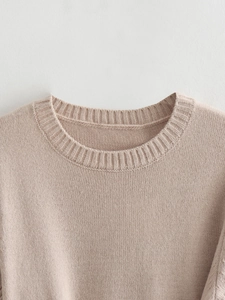 Close-up of the ribbed crew neck and fine texture on a beige knitted short sleeve top