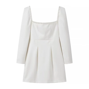 Detailed view of the square neckline and delicate pearl trim on white long sleeve dress