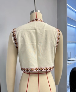 Detailed back view of off-white vest showing colorful floral embroidery patterns