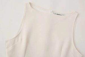 Détail de l'encolure d'une robe blanche sans manches avec fermeture éclair et étiquette BBWM WOMAN