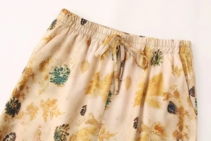 Detail of elastic drawstring waistband on beige autumn leaf print trousers