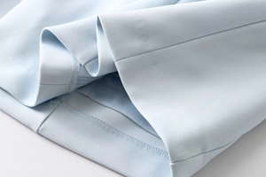 Close-up detail of light blue dress hemline with high-quality double-needle stitching