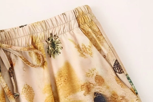 Detail of elastic drawstring waist on tropical pineapple print trousers with satin texture