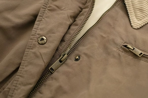Detail of jacket with metal zipper, star-patterned snap button and corduroy collar