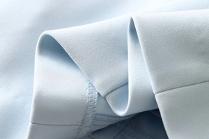 Close-up detail of light blue high-density knit fabric with fine stitching and hemline