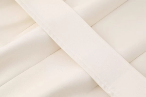 Gros plan détaillé du tissu beige de la robe montrant des coutures professionnelles