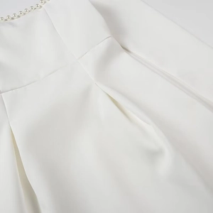 Detailed view of white mini dress neckline with elegant pearl beads and pleats