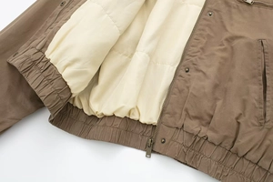 Detailed view of elastic gathered hem and metal zipper on the two-tone bomber jacket