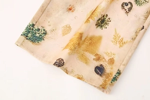 Detailed close-up of vintage leaf and fruit print on lightweight beige chiffon fabric