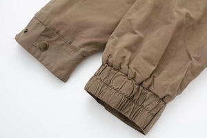 Detailed close-up of dark brown bomber jacket cuffs with metallic snap buttons and stitching