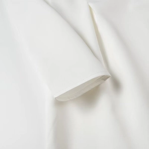 Detailed close-up of white A-line dress showing fine woven fabric and neat stitching