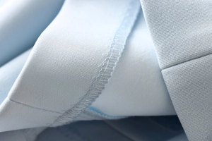 Detailed close-up showing light blue dress fabric texture and precision seam stitching