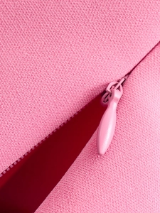 Close-up of pink fabric texture and matching invisible zipper for summer slim fit top