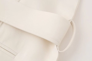 Détail de la taille en tissu tissé avec passants de ceinture sur la robe blanc crème