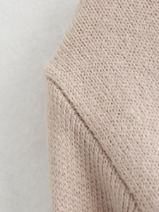 Detailed close-up of soft beige knit fabric showing shoulder seam and fine texture