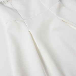 Detailed macro view of white A-line dress with pearl trim on neckline and fine seams