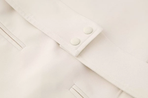 Gros plan détaillé des doubles boutons recouverts de tissu et des coutures sur la robe beige
