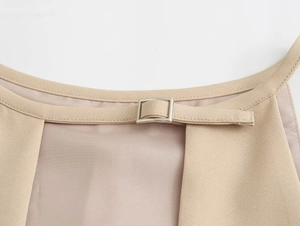 Dettaglio della fibbia quadrata regolabile sul top beige con trama in tessuto twill
