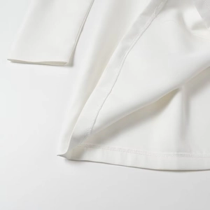 Detailed macro view of neat stitching on white square neck dress hem and cuffs