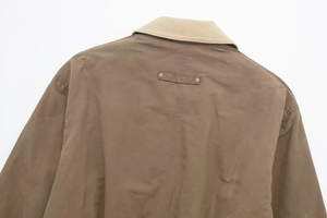 Detail view of the brown bomber jacket with beige corduroy collar and metal rivets