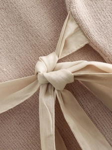 Macro shot of apricot pink knit texture and elegant ribbon bow detail on sleeve