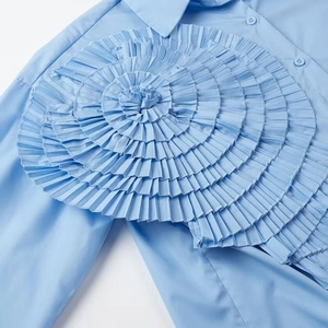 Detailed view of the light blue shirt showing 3D floral ruffles and cotton texture