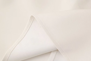 Gros plan sur la texture du tissu blanc crème et les coutures fines de la robe d'été
