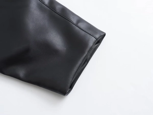 Détail de la veste en cuir noir avec texture grainée et coutures doubles précises