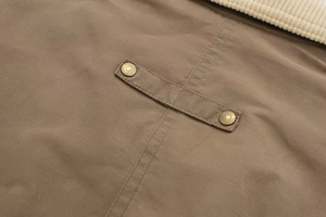 Macro detail of brown cotton twill bomber jacket with vintage metal snap buttons and corduroy collar