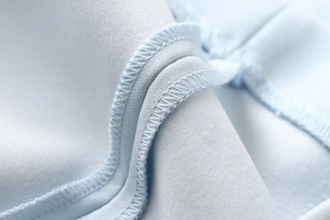 Close-up of overlock stitching and knit fabric detail on the light blue summer dress