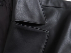 Détail de la veste en cuir noir montrant les coutures précises et la texture de la matière