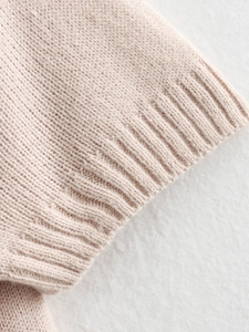 Detailed macro shot of the ribbed cuff and soft knit fabric on this pink summer top