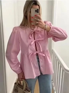 Detail of pink long-sleeve blouse featuring three elegant front bow tie closures