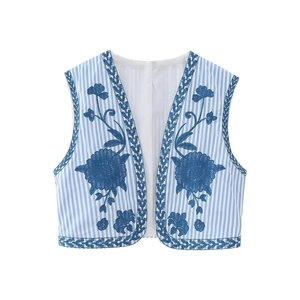 Detailed close-up of blue floral embroidery and woven trim on a striped vintage vest