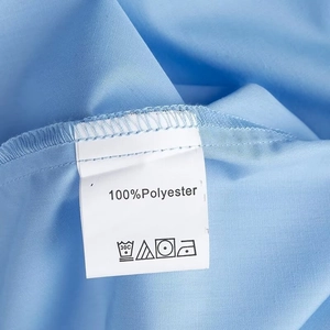 Macro shot of 100% polyester light blue fabric with washing care label and texture details