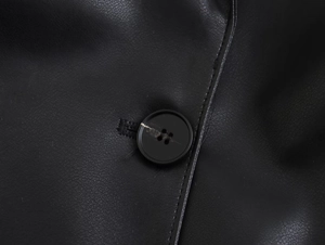 Détail de la texture cuir synthétique avec bouton noir et finitions de couture précises