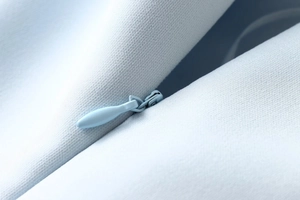 Detailed close-up of a matching invisible zipper on light blue textured summer dress fabric