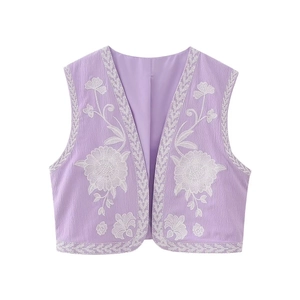 Detail of lavender cotton vest featuring white floral embroidery and v-neck open front