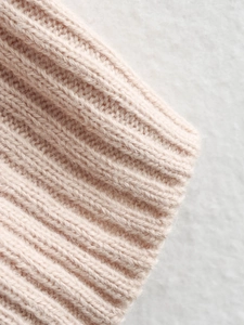 Close-up macro of soft light pink ribbed knit fabric showing detailed texture and wool blend fibers