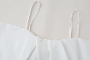 Detail shot of white poplin top featuring slim straps and pleated neckline design
