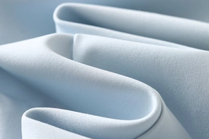 Close-up of the light blue woven fabric texture with dense S-shaped draped folds